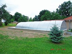 Schwimmbadbau, hier: Schwimmbadneubau. Sie sehen ein Folienbecken mit einer geöffneten 10m-Segmentschiebehalle.